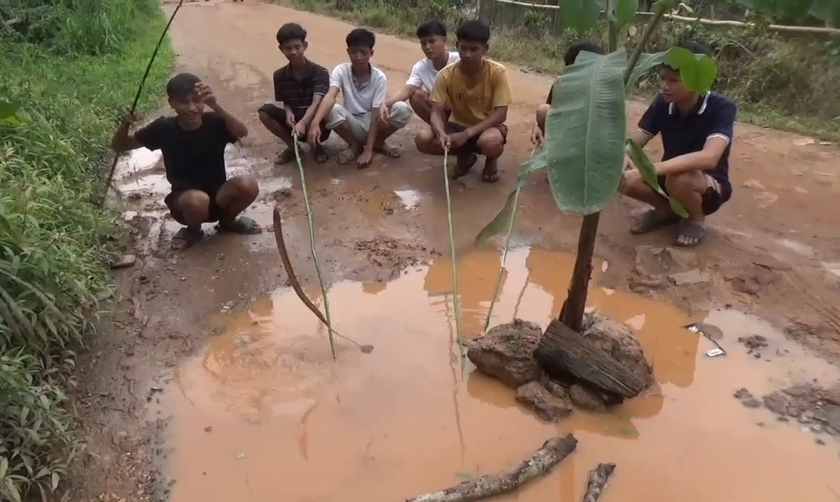 Kritik Pemerintah, Sejumlah Pemuda di Desa Mudung Darat, Kecamatan Maro Sebo, Kabupaten Muaro Jambi Mancing Belut dan Tanam Pohon di Jalan Rusak, Sabtu 12 April 2025.